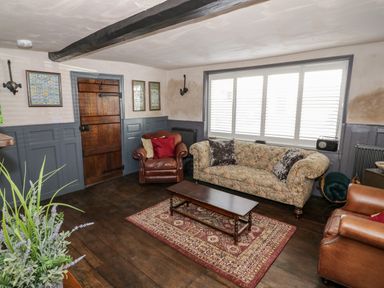 A sitting room with two leather armchairs a patterned sofa coffee table and a rug at The Old Paper Shop in Tewkesbury