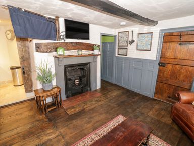 A room with a fireplace television wooden door and wooden floors at The Old Paper Shop in Tewkesbury