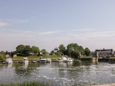A marina with boats docked along the water and greenery in the background at The Old Paper Shop in Tewkesbury