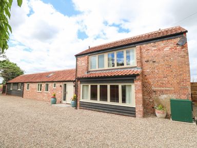 A brick and timber house with multiple windows and a gravel driveway at Cobblers Barn in Repps With Bastwick near Potter Heigham