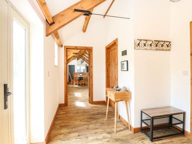 A hallway with wooden floor beams a small wooden table and wall hooks at Cobblers Barn in Repps With Bastwick near Potter Heigham