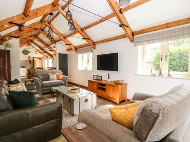 A living room with sofas a coffee table and a wall-mounted TV at Cobblers Barn in Repps With Bastwick near Potter Heigham