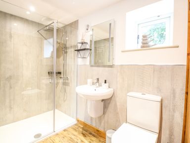 A bathroom with a shower enclosure a sink a toilet and a small window at Cobblers Barn in Repps With Bastwick near Potter Heigham