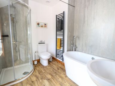 A bathroom with a corner shower, toilet, towel rack, bathtub, and sink at Cobblers Barn in Repps With Bastwick near Potter Heigham