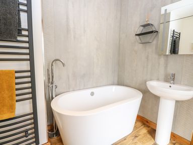 A bathroom with a freestanding bathtub sink and towel rack at Cobblers Barn in Repps With Bastwick near Potter Heigham