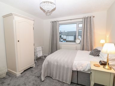 A bedroom with a bed next to a window and a wardrobe against the wall at Cranberry in Bude
