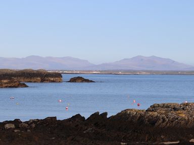 A coastal scene with rocks in the foreground water with buoys and distant mountains at The Granary - Rhoscolyn
