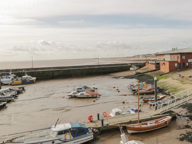 A harbor with boats on a dry dock at low tide and buildings by the water at Shore Thing 280 in Wilsthorpe