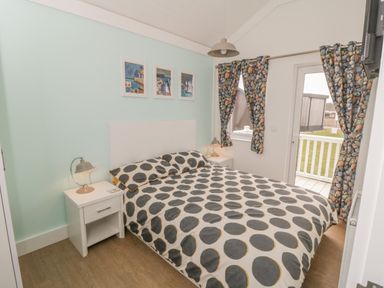 A bedroom with a double bed bedside tables lamps and curtains with a pebbled pattern at Shore Thing 280 in Wilsthorpe