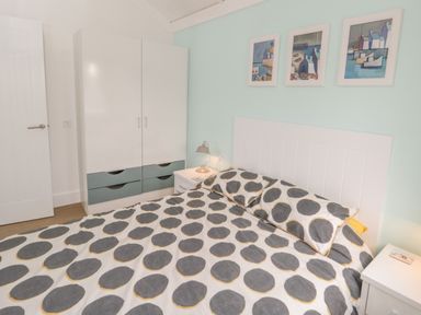 A bedroom with a bed covered in polka dot bedding a wardrobe and three framed pictures on the wall at Shore Thing 280 in Wilsthorpe