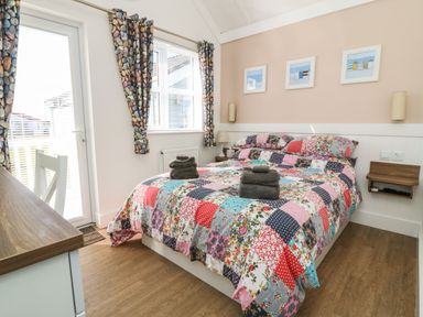 A bedroom with a double bed covered with a patchwork quilt and folded towels on top at Shore Thing 279 in Wilsthorpe