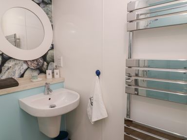 A bathroom sink with a round mirror above and a chrome towel rack at Shore Thing 279 in Wilsthorpe