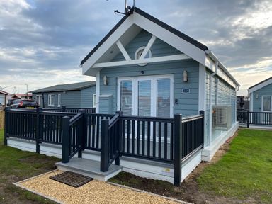 A small blue cabin with white trim and black railing on a porch at Shore Thing 279 in Wilsthorpe