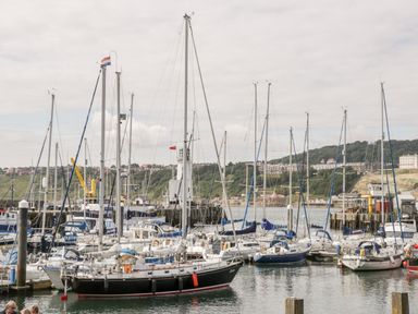 Sailboats docked in a harbor with buildings and hills in the background at Royal Victoria House in Scarborough