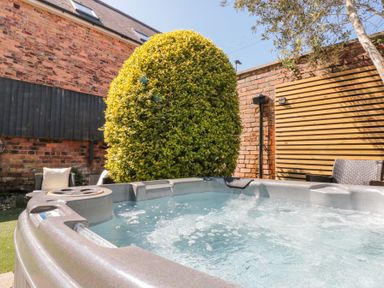 An outdoor hot tub with bubbling water near a bush and patio chairs at Royal Victoria House in Scarborough