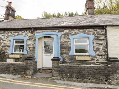 Front of a stone cottage with two windows and a door framed in blue at Crud yr Awel in Braichmelyn near Bethesda