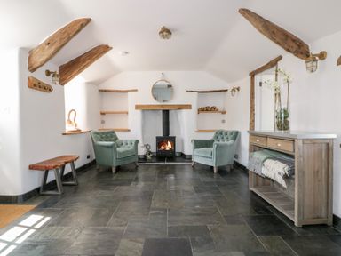 A sitting room with two armchairs and a wood-burning stove at Harbour Cottage in Boscastle
