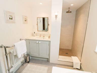A bathroom with a sink vanity a mirror a walk-in shower and a towel rack at Prospect Cottage in Malvern Wells near Great Malvern