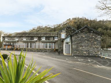 A stone building with multiple windows and parking spaces in front at Lowe-McConnell in Far Sawrey