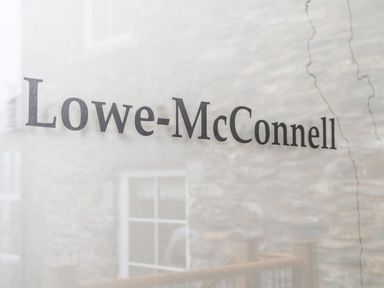 Text Lowe-McConnell on a translucent surface with a stone wall and window behind it at Lowe-McConnell in Far Sawrey