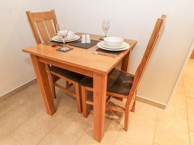 A wooden dining table with two chairs set with plates bowls glasses cutlery and salt and pepper shakers at Lowe-McConnell in Far Sawrey