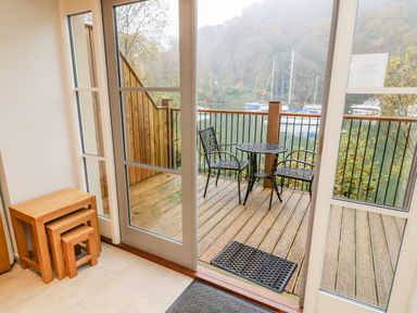 A patio with metal table and two chairs outside glass doors overlooking a body of water at Lowe-McConnell in Far Sawrey