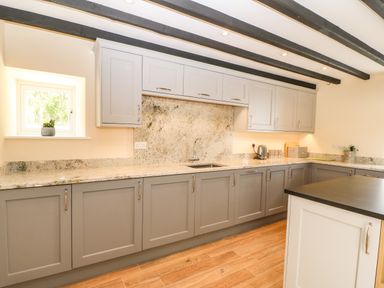 A kitchen with grey cabinets a countertop with a sink and a small window with a plant on the sill at Trewen Botwnnog near Sarn Meyllteyrn