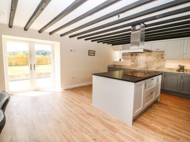 A kitchen with an island counter wooden floor and double glass doors opening to a garden at Trewen Botwnnog near Sarn Meyllteyrn