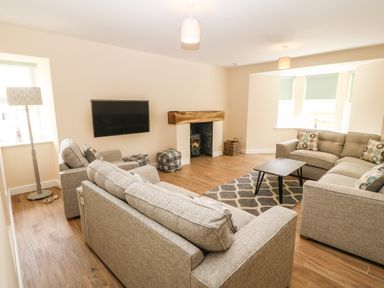 A living room with sofas a wall-mounted TV a fireplace and a coffee table at Trewen Botwnnog near Sarn Meyllteyrn