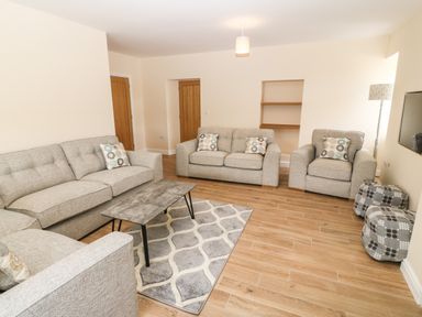 A living room with three sofas a coffee table a rug wooden floor and a floor lamp at Trewen in Botwnnog near Sarn Meyllteyrn