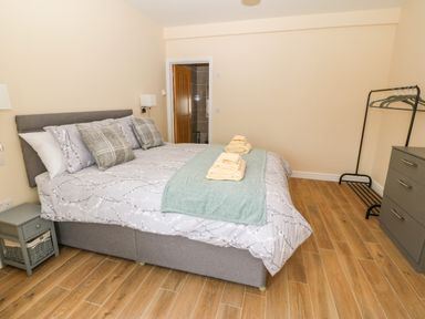 A bedroom with a double bed towels on the bed a bedside table clothes rack and chest of drawers at Trewen Botwnnog near Sarn Meyllteyrn