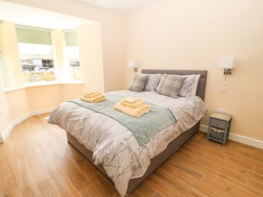 A bedroom with a bed with pillows and folded towels near a bay window at Trewen Botwnnog near Sarn Meyllteyrn