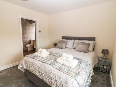A bedroom with a double bed pillows bedside tables and an ensuite bathroom at Trewen in Botwnnog near Sarn Meyllteyrn