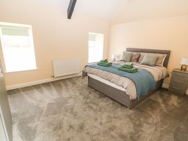 A bedroom with a double bed with green towels on it and bedside tables with lamps at Trewen in Botwnnog near Sarn Meyllteyrn