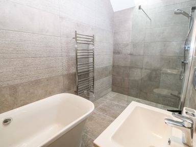 A bathroom with a bathtub sink towel rack and walk in shower at Trewen in Botwnnog near Sarn Meyllteyrn