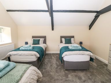 A bedroom with two single beds with blue blankets and pillows and a green bed with towels on it at Trewen Botwnnog near Sarn Meyllteyrn