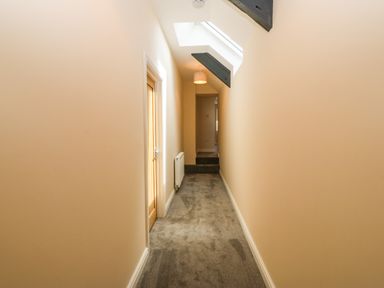 A hallway with beige walls grey carpet and a skylight at Trewen in Botwnnog near Sarn Meyllteyrn