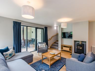A living room with sofas chairs a coffee table and a TV mounted on the wall at Wildcat Lodge in Feshiebridge near Aviemore