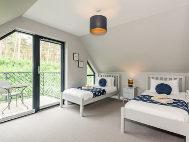 A bedroom with two single beds beside a balcony door at Wildcat Lodge in Feshiebridge near Aviemore