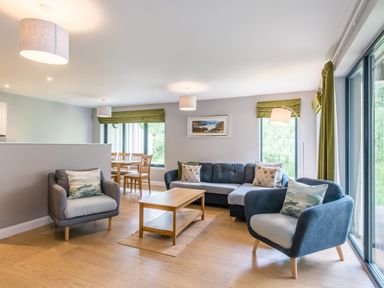 A living room with chairs a sofa and a wooden coffee table at Golden Eagle Lodge in Aviemore