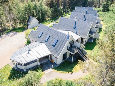 An aerial view of a row of houses with blue roofs surrounded by trees and grass at Golden Eagle Lodge in Aviemore