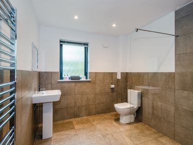 A bathroom with a pedestal sink toilet towel rack and window at Red Deer Lodge in Feshiebridge near Aviemore
