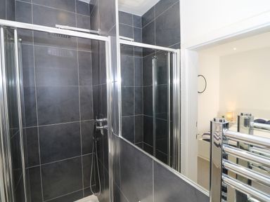 A bathroom with a glass shower enclosure and a view into a bedroom at Arlanfor in Rhosneigr