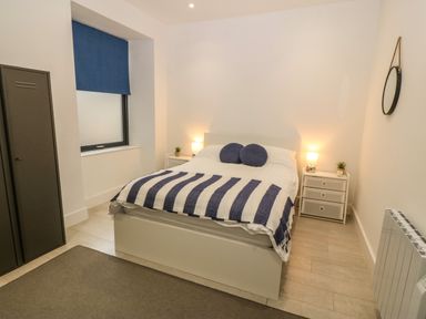 A bedroom with a bed blue and white striped blanket and two round pillows at Arlanfor in Rhosneigr