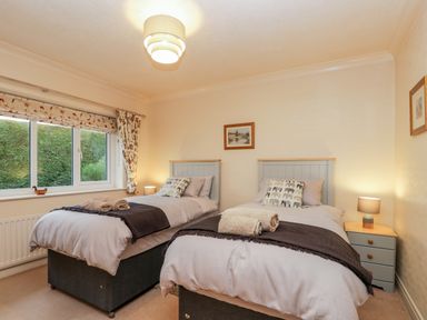 A bedroom with two single beds bedside tables and a window at Sanderling in Scalby