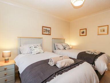 A bedroom with two single beds bedside tables and framed pictures on the walls at Sanderling in Scalby