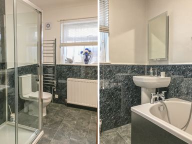 A bathroom with a shower enclosure toilet radiator and a vase with flowers on the window at Sanderling in Scalby