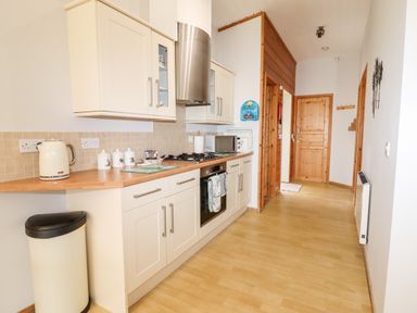 A kitchen with white cabinets wooden countertops a stainless steel oven and cooker hood and a wooden door at Watersview Lodge Rudyard near Leek