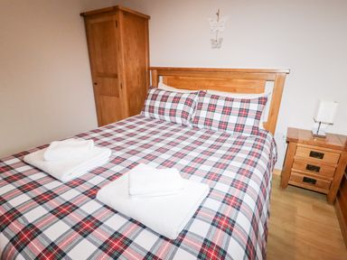 A bedroom with a wooden bed and wardrobe two bedside tables and a lamp at Watersview Lodge in Rudyard near Leek