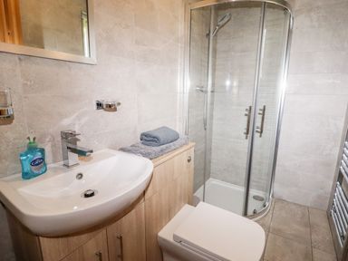 A bathroom with a sink soap dispenser shower toilet and folded towels at Watersview Lodge Rudyard near Leek